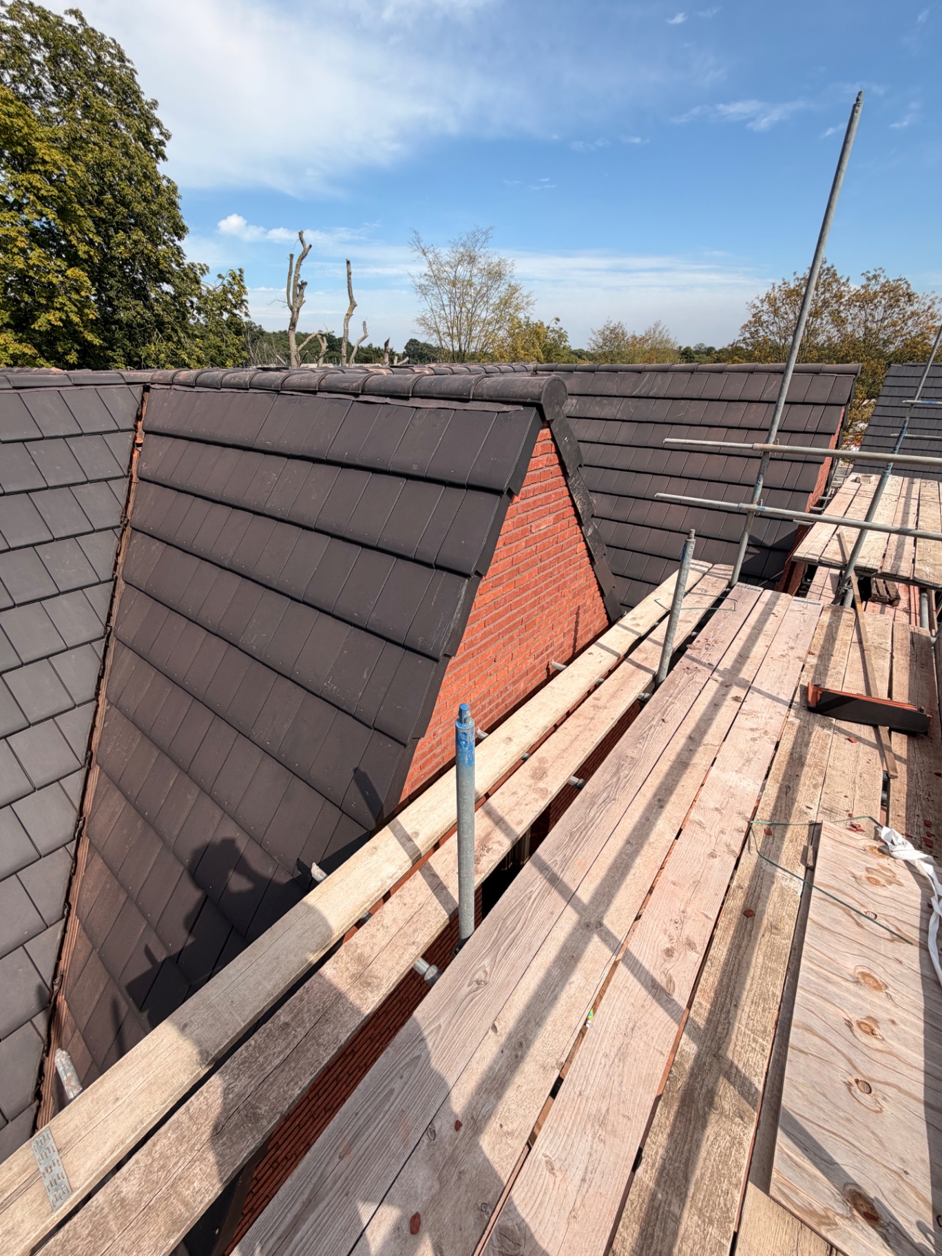 Nieuw gelegde antracieten dakpannen op een woning met steiger